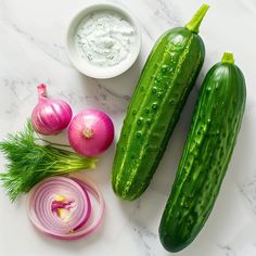 cucumbers, onions, and other vegetables on a marble countertop with dip