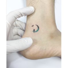 a person holding their foot with a small tattoo on it's left ankle and an arrow in the middle