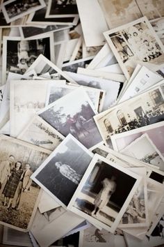 old black and white photographs are scattered on the floor in a pile, with one person standing among them