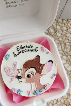 a decorated cake in a white box with pink tissue paper on the bottom and an image of a deer