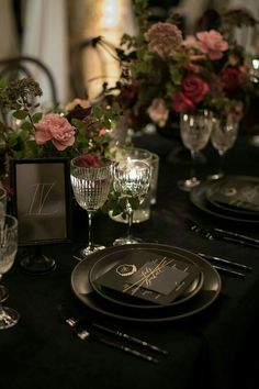 the table is set with black plates and silverware