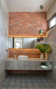 an instagram photo of a bathroom with brick walls and concrete countertops, along with a plant in the corner