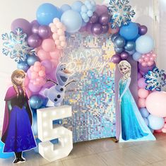 frozen princess birthday decorations and balloons with the number five in front of an ice queen backdrop