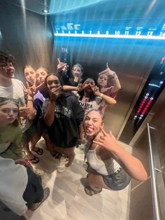 a group of people standing in front of an escalator with their hands up