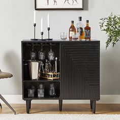 a cabinet with liquor bottles and glasses on it in front of a wall mounted art