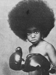 an old photo of a young boy wearing boxing gloves