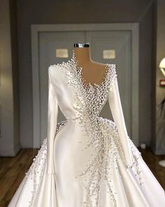 a white wedding dress with long sleeves and beading