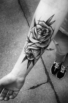 a black and white photo of a rose tattoo on the arm