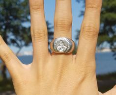 a woman's hand with a ring on it that has a lion head in the middle