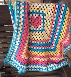 a crocheted blanket sitting on top of a wooden bench