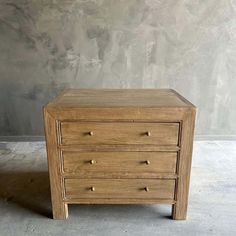 a small wooden chest of drawers on concrete floor