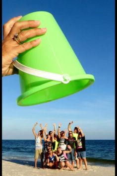 a group of people standing on top of a sandy beach under a green cone shaped object