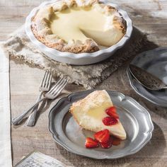 a piece of cheesecake on a plate with strawberries next to it and a fork