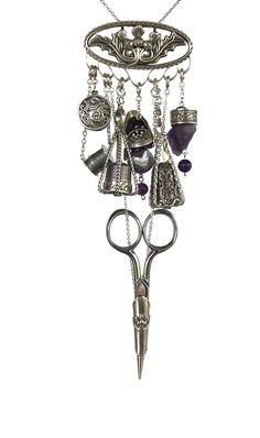 a pair of scissors and some charms hanging from it's holder on a chain