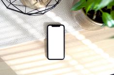 a cell phone sitting on top of a table next to a potted plant