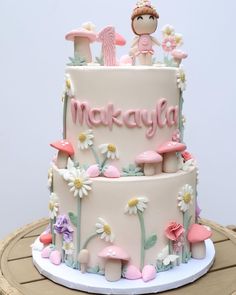 a three tiered cake decorated with flowers, mushrooms and the word maryga on it