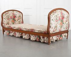 an antique daybed with floral upholster and ruffles on the sides