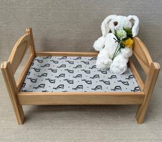 a white teddy bear sitting on top of a wooden bed