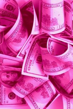 a pile of one hundred dollar bills sitting on top of each other in pink light