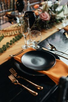 a table set with black plates and silverware