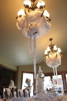 a chandelier hanging from the ceiling above a table covered in white linens