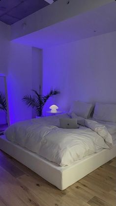 a white bed sitting in a bedroom next to a blue light on the wall above it