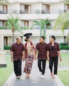 three men and a woman walking down the street in front of an apartment building with palm trees