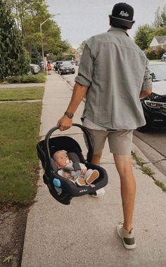 a man walking down the sidewalk with a baby in a stroller