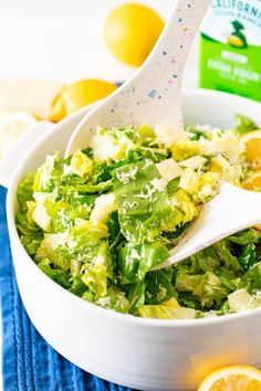 a white bowl filled with salad next to lemons