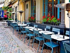 an outdoor dining area with blue chairs and tables in front of a building that says the best older patas i tison