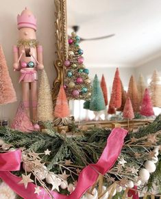 a christmas mantel decorated with pink, green and gold ornaments including a nutcracker