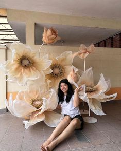 a woman sitting on the ground with flowers in front of her