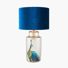 a glass lamp with a blue shade on the top and a peacock painted on it