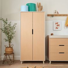 a wooden cabinet sitting in the corner of a room next to a potted plant