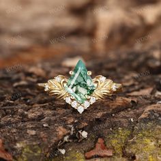 a ring with green and white stones on it sitting on top of a tree stump