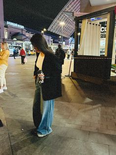 a woman standing on the sidewalk looking at her cell phone