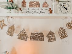 gingerbread cut out houses hanging on a string in front of a clock and other decorations