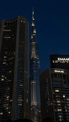 the burj building is lit up at night in front of other tall buildings