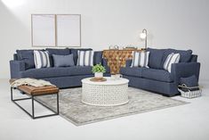 a living room with blue couches and pillows on the floor, coffee table in front of them