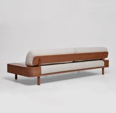 a wooden and white couch sitting on top of a white floor next to a wall