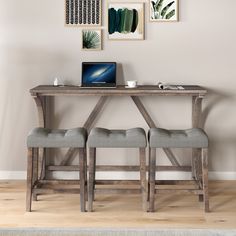 two grey chairs sitting at a table with a laptop on it and pictures above them