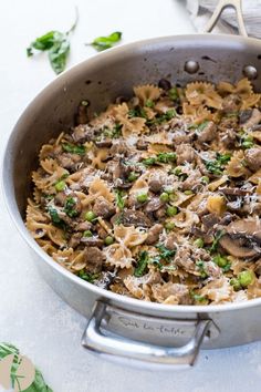 a pan filled with pasta and mushrooms on top of a table