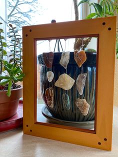 a potted plant sitting on top of a table next to a mirror with shells in it