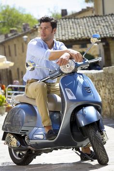 a man riding on the back of a blue scooter