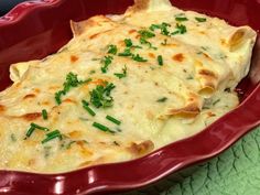 a casserole dish with cheese and chives in a red bowl on a green place mat