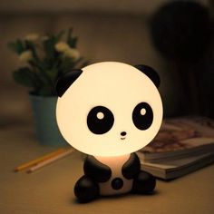 a panda bear lamp sitting on top of a table next to a book and plant