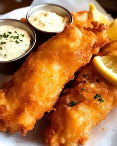 fried fish with dipping sauces and lemon wedges