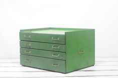 a green file cabinet sitting on top of a wooden floor next to a white wall