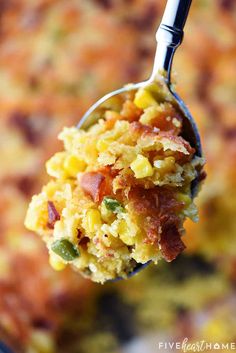 a spoon full of food that is on top of a casserole dish with bacon and green beans