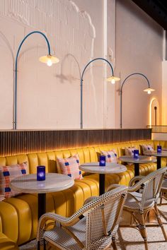 an empty restaurant with yellow leather booths and blue lamps on the wall, along with white walls